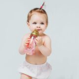 happy girl diaper with cute hairstyle holds bottle milk